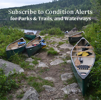 Four canoes on a rocky shore of a river.
