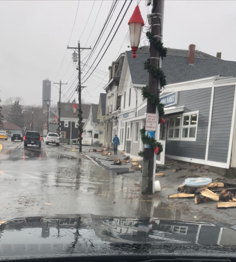 A flooded street with gray buildings.