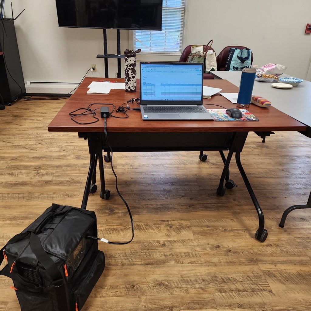 A table with a computer attached to a battery in a black bag.