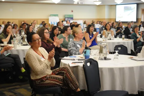 Community members applauding at a Stronger Communities Summit conference.